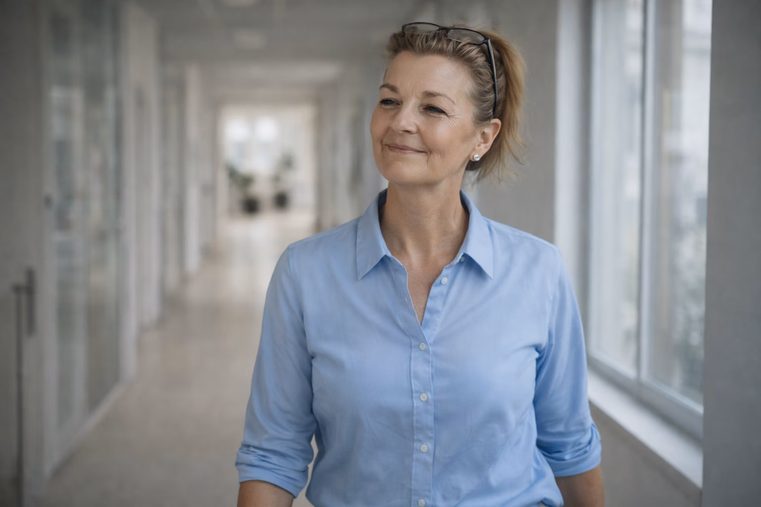 Susanne Sommer steht ruhig und präsent in einem hellen Business-Flur.