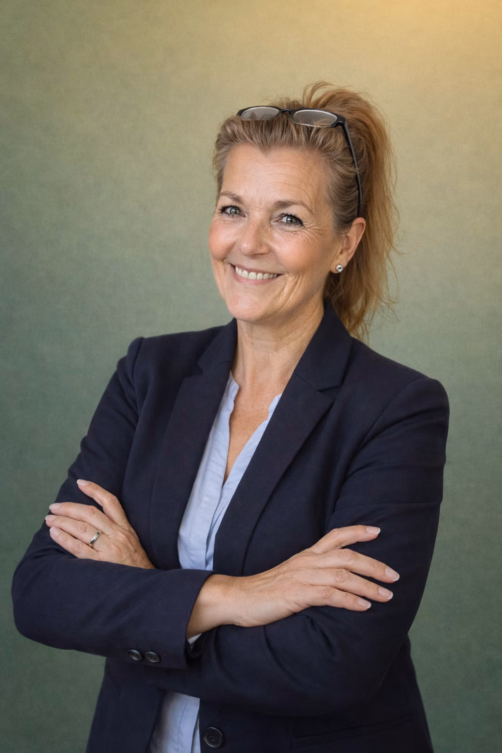 Susanne Sommer lächelt im Business-Outfit mit verschraenkten Armen.